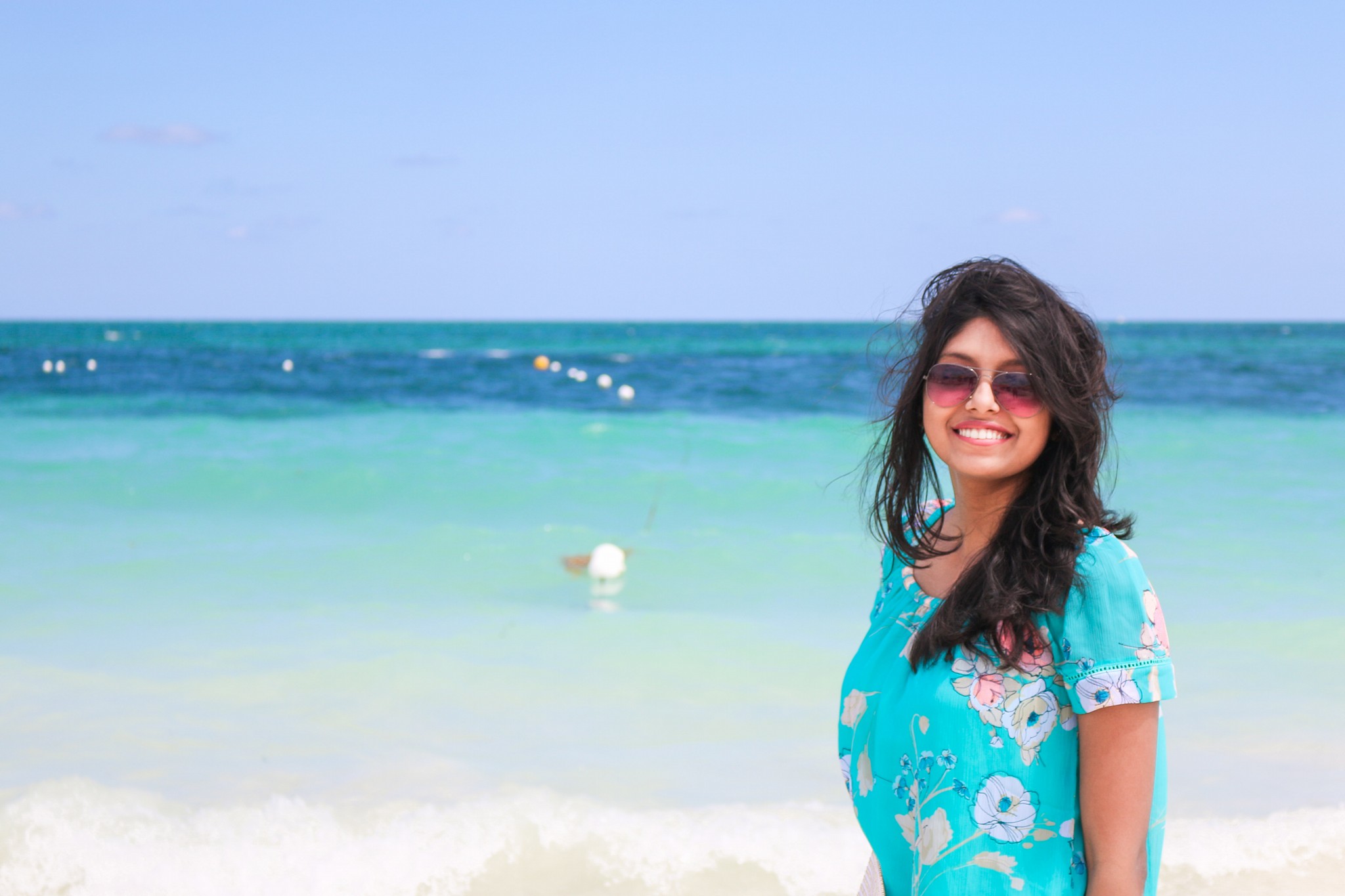 Maitraye is smiling at camera in front of pristine blue ocean in Bahamas