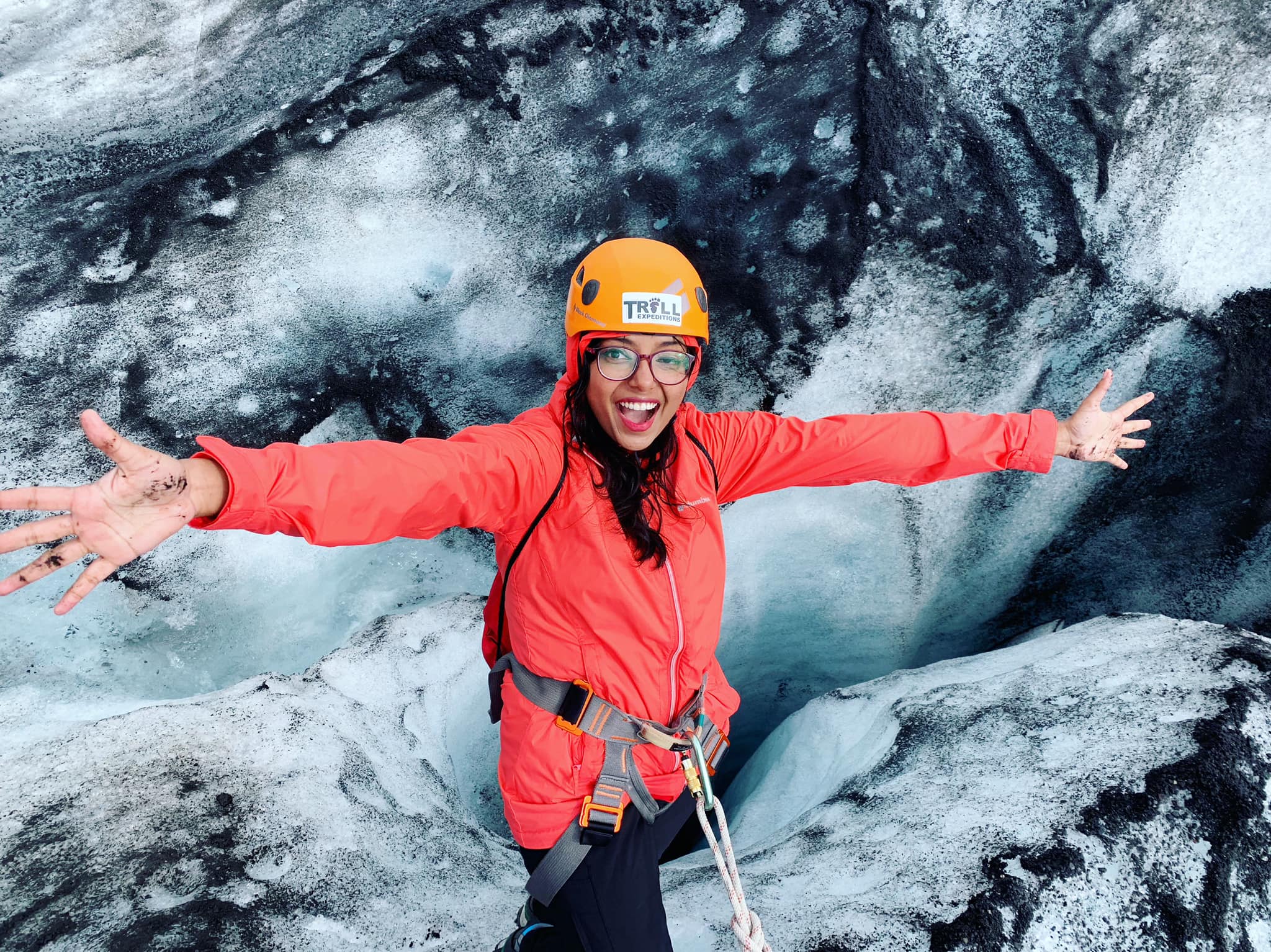 Maitraye is smiling at the camera while hanging near a crevasse in Solheimajokull glacier, Iceland